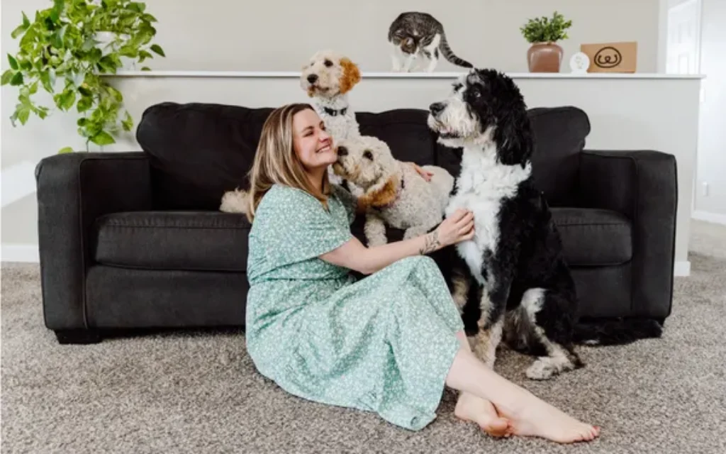a woman sitting on the floor with several dogs while using a Diffuser